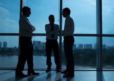 Three Business Men Talking By Window